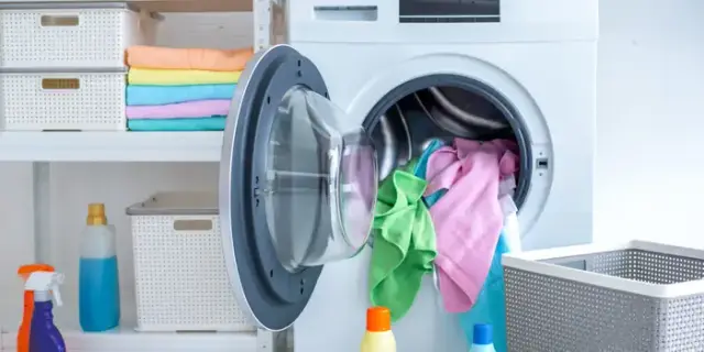 Front view of an opened washing machine with clothes hanging out Front view of an opened washing machine with clothes hanging out