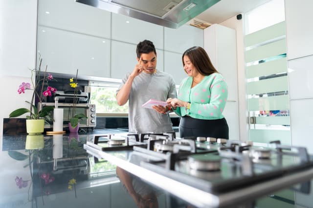 Front view of a man shopping for a gas cooktop and range hood as a woman helps him Front view of a man shopping for a gas cooktop and range hood as a woman helps him