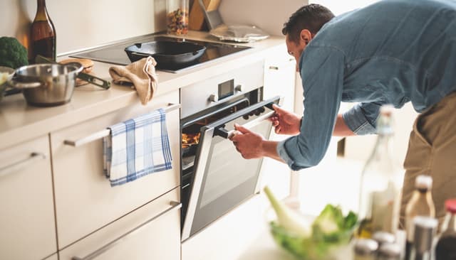 View of a man peeking inside his air fry oven