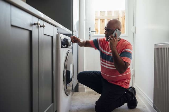 Front view of a man calling for help with his washing machine Front view of a man calling for help with his washing machine