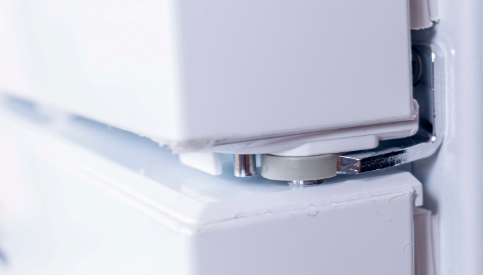 Close-up of a white refrigerator door hinge between the upper and lower doors