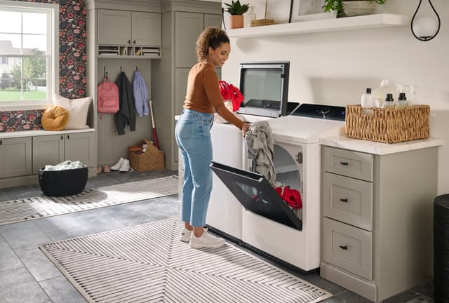 Front view of a woman moving clothes from her washer to dryer Front view of a woman moving clothes from her washer to dryer