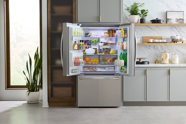Front view of a modern kitchen with an opened LG french door refrigerator
